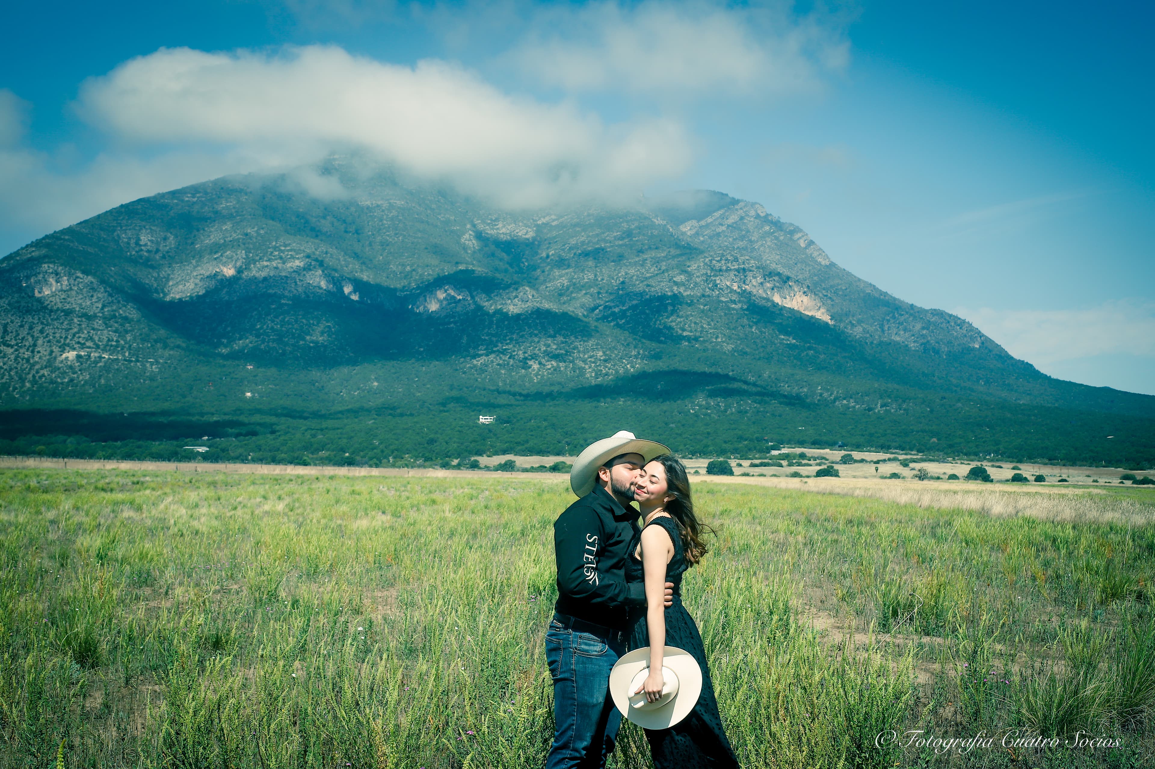 Una pareja abrazada frente a un paisaje de montañas